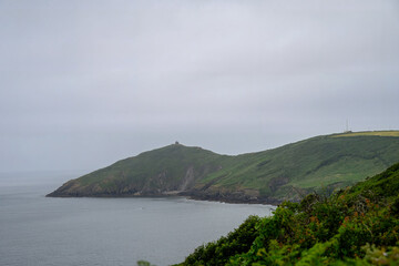 the South West Coast path along the Rame Peninsula in Mount Edgcumbe Country Park Cornwall England on a misty summer day with Rame Head Chapel in the background