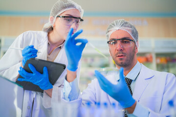 scientists perform experiments and record data. people arranges equipment with test tubes and chemicals for producing medicine and biochemistry. man hold tubes of chemical liquids and plant samples.