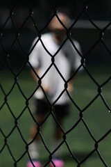 Mini soccer field with fence and blurred players in the background, selective focus
