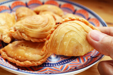 Closeup of Hand Picking a Thai Curry Puff, Popular Snack Similar to Empanadas and Samosa