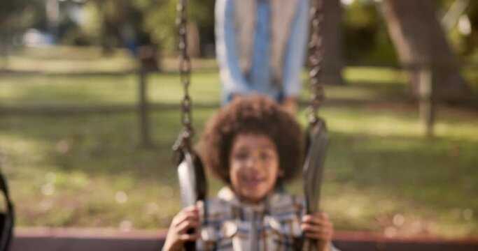 Mother, child and playing with swing at park for fun ride, bonding or outdoor holiday weekend in nature. Happy little boy, child or kid with parent in joy, happiness or cheerful playground in woods
