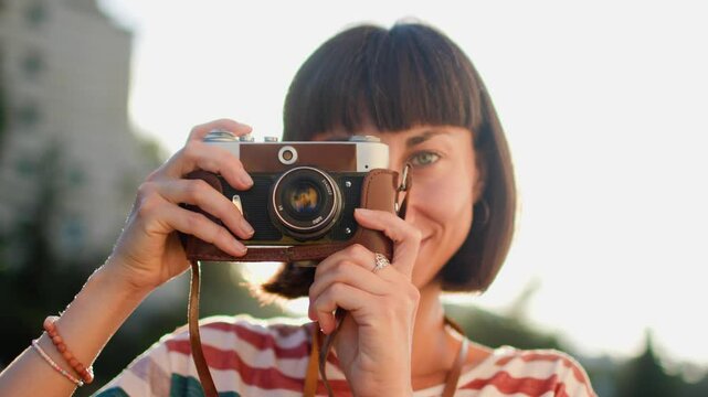 young girl with a camera. Fashionable and attractive beautiful woman with analog film camera takes photos during sunset, 
creates content.  travel and vacation.