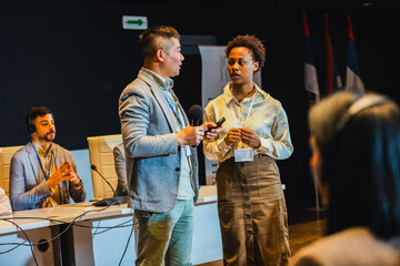 Asian and African American business people having speach on a press conference in a convention center.