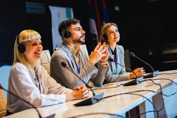 Business people wearing headphones on for translation at press conference in convention center.