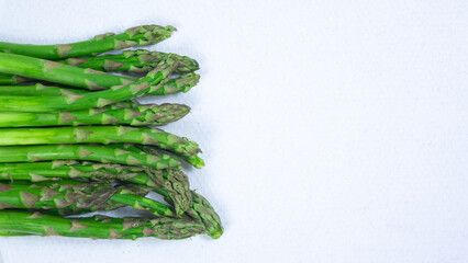 Green asparagus stems on a white cutting board. The importance of eating vegetables.