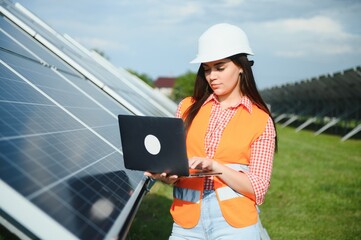 Fototapeta premium Beautiful young woman near solar panels outdoors