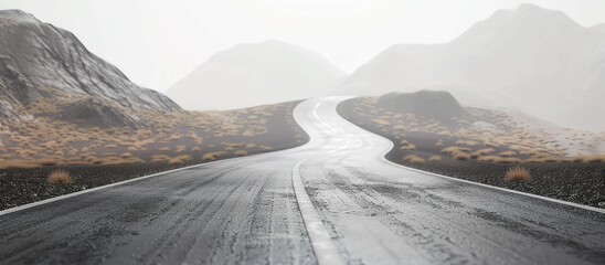 Fototapeta premium The image shows an empty asphalt road winding through a mountainous landscape.