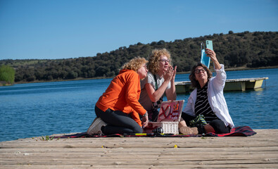Middle-aged sisters taking a selfie by the lagoon