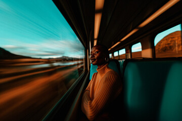A person wearing headphones and a sweater is seen looking out the window while traveling on a train, with the blurred landscape rushing by outside, evoking a sense of contemplation.