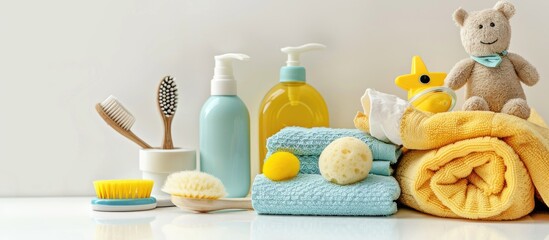 Children's cleanliness items like a baby's sponge, bottles, hairbrush, and a newborn's towel displayed on a white background with copy space image.