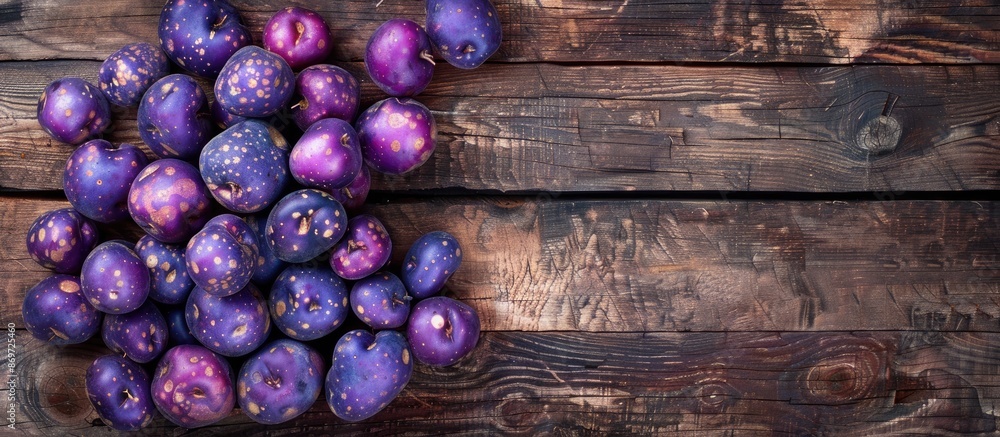 Poster top view of vibrant purple potatoes on rustic wood surface with ample copy space image.