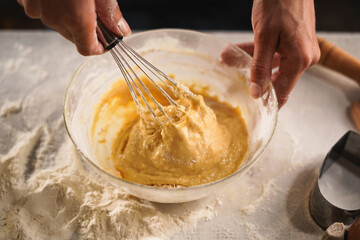 Pastry chef making dough with a whisk. cooking waffle on rustic wooden table with ingredients. Handmade dessert and cooking process