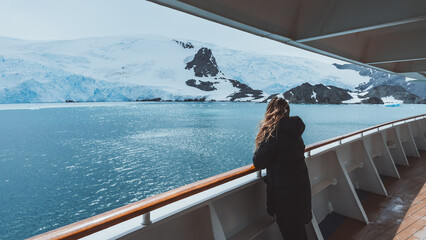 Antarctica Female Cruise Passenger Views Glacier. Beautiful Girl Hair Blowing in Wind on Side Railing Adventure Expedition Landscape Nature Wide Deck © And They Travel