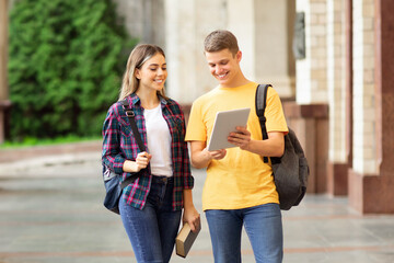 Classmates preparing for lecture with digital tablet, having break outdoors