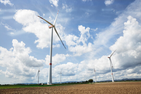 Windfarm surrounded by fields of corn, wheat and sunflowers with blue skies and clouds. Freckenfeld, Germany