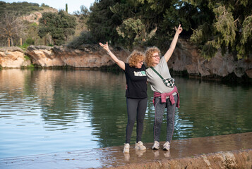 three middle-aged sisters posing by a lake after a hike