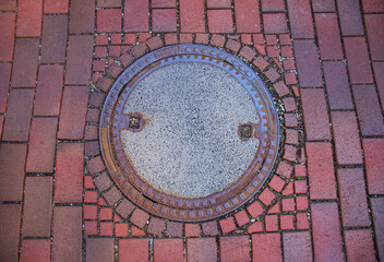 Manhole on the red paving stone road