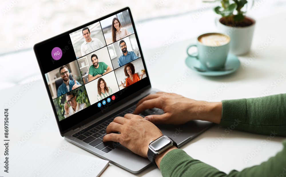 Poster freelancer is sitting at a desk in front of a laptop and participating in an online video conference