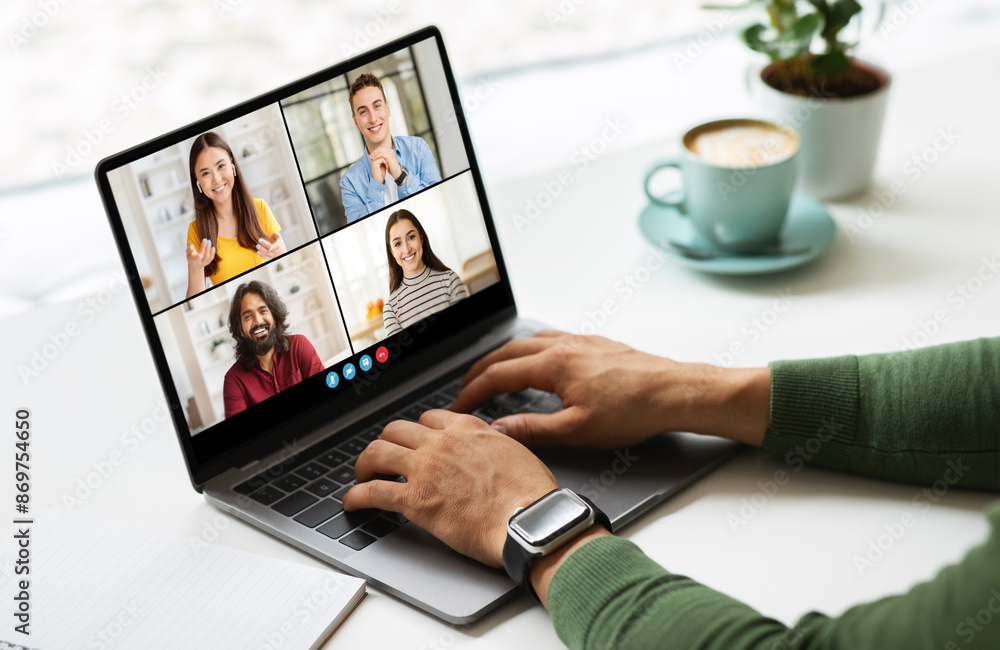 Poster black man sits at a table, using his laptop to participate in a video conference call. he is typing 