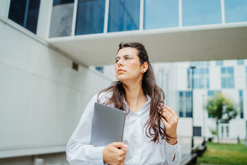 Fototapeta premium One beautiful young successful business woman going to work at business office modern building while holding laptop and wearing glasses 