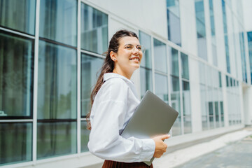 Fototapeta premium One beautiful young successful business woman going to work at business office modern building while holding laptop and wearing glasses 