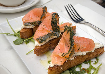herbed salmon lox on toast with cream cheese (breakfast gravlax open faced sandwiches) arugula lemon drizzle (dill crust fish with herbs) toast bread toasted fork plate brunch restaurant meal seafood