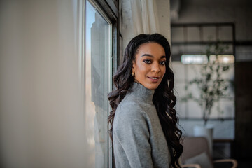 Close-up of an african-american woman standing at the window and smiling