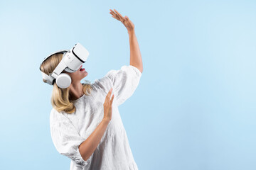 Skilled girl in pajamas excited with metaverse by using VR goggle at background. Caucasian woman...