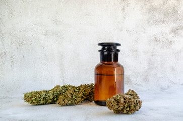 Frasco de vidrio médico y cosméticas con aceite CBD cerca de cogollos verdes de cannabis sativa...