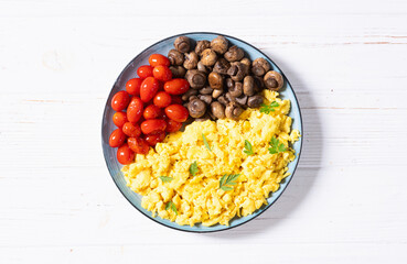 Homemade scrambled eggs with mushrooms and cherry tomatoes