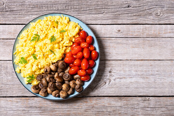 Homemade scrambled eggs with mushrooms and cherry tomatoes