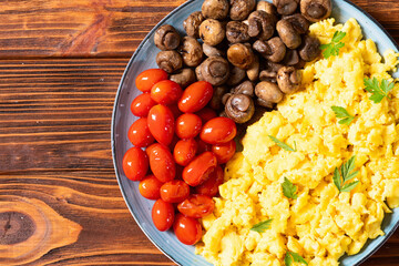 Homemade scrambled eggs with mushrooms and cherry tomatoes