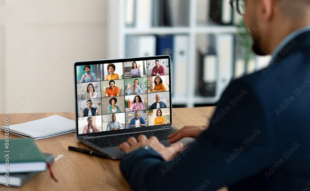 Poster a businessman sits at a desk with a laptop open in front of him, showing a video conference screen w