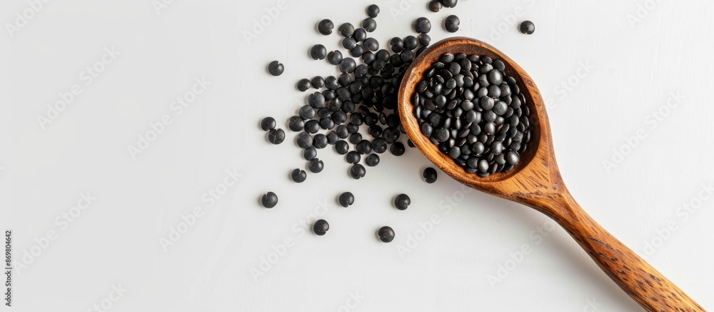 Poster black lentils beans with a wooden spoon against a white backdrop with room for text or other element