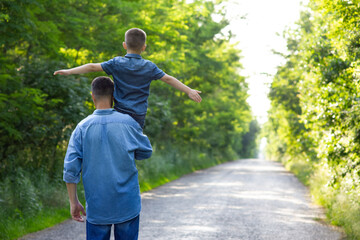 A Happy child on the shoulders of a parent in nature on the way to travel