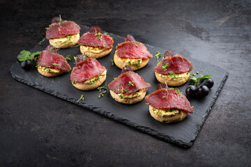 Traditionally marinated lamb salmon on rye cheese with curry cream cheese and red grapes served as appetizers on a design tray
