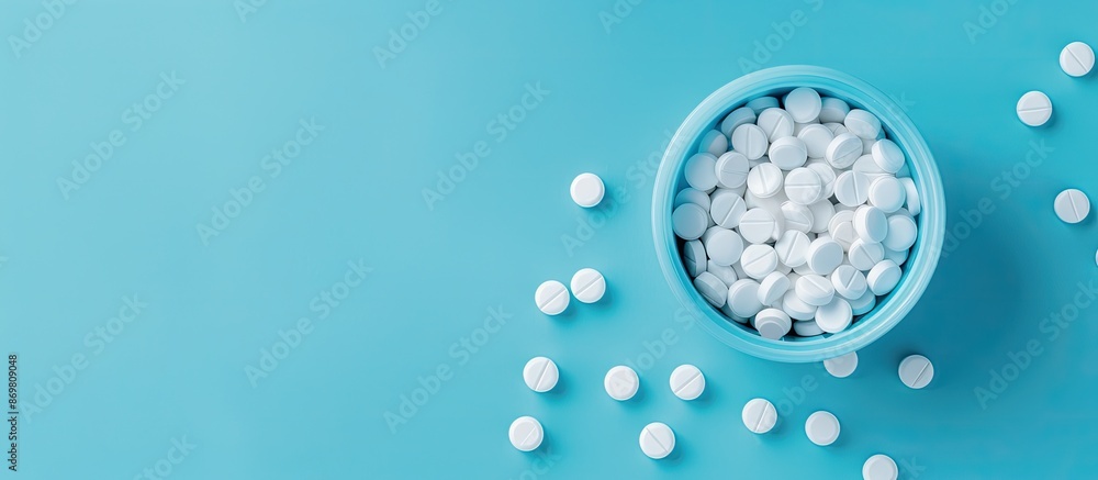 Poster Flat lay top view of a spilled circle pill container on a blue background, focusing on the pills with an isolated setting for medical themes with copy space image.