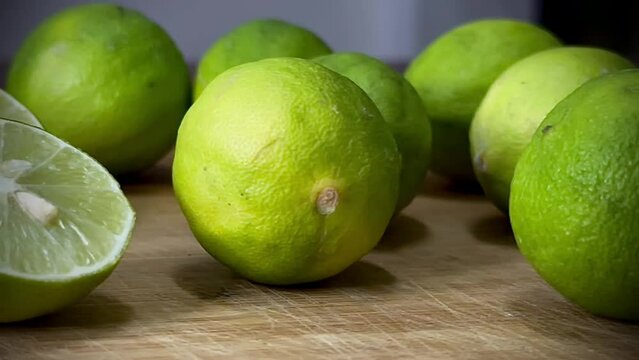 Fresh green lemons with sliced pieces on blurred background 
