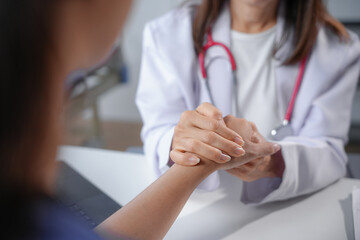 Female doctor comforting patient by holding her hand