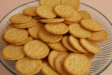 Saltine crackers in a transparent dish on a pink background close-up, cookies in a vase, cookies for tea