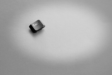 Escape key on a light background in a beam of light, black-and-white picture, end of work, only way...
