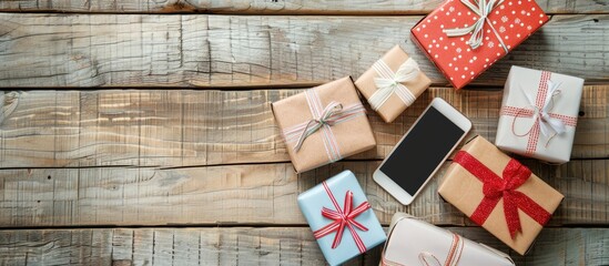 Obraz premium Gift boxes arranged around a mobile phone on a wooden surface, creating an appealing composition with a copy space image.