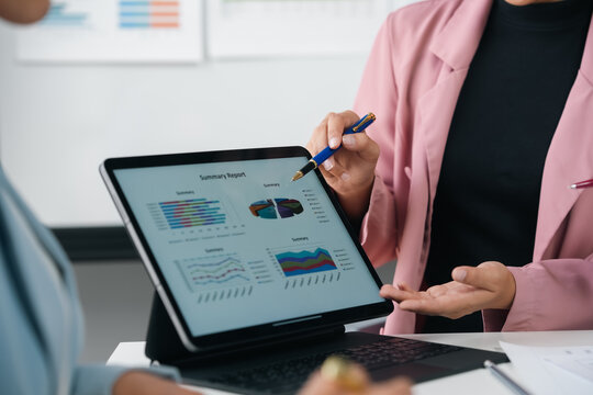 Businesswoman pointing at charts on tablet during meeting