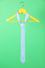 Hanger with light blue tie on green background