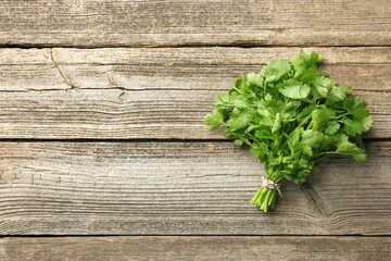 Bunch of fresh coriander on wooden table, top view. Space for text