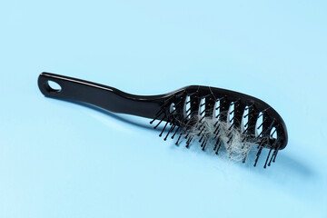 Brush with lost hair on light blue background