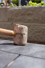 Man laying composite decking tile patio with a rubber mallet. Garden home improvements concept.