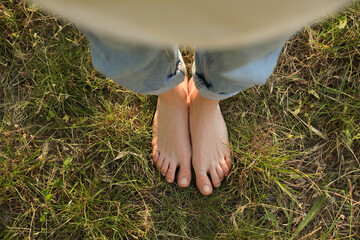 Woman standing barefoot on green grass outdoors, top view