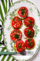 Fried zucchini slices with tomatoes and garlic mayonnaise on a platter