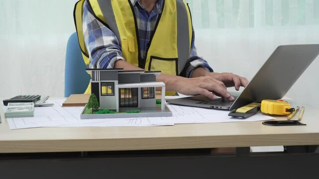 Professional architect team and engineer discuss about architectural project on meeting table with safety helmet, wooden block and architectural document scatter around. Closeup. Delineation.